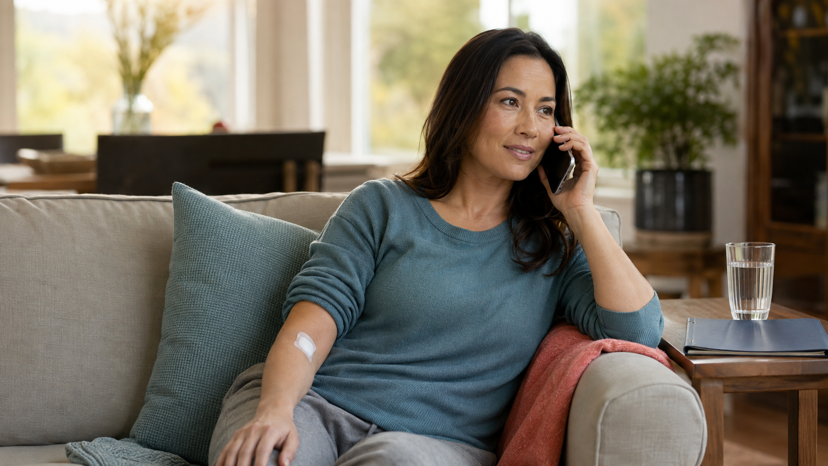 A woman resting at home with an arm bandage while speaking on the phone